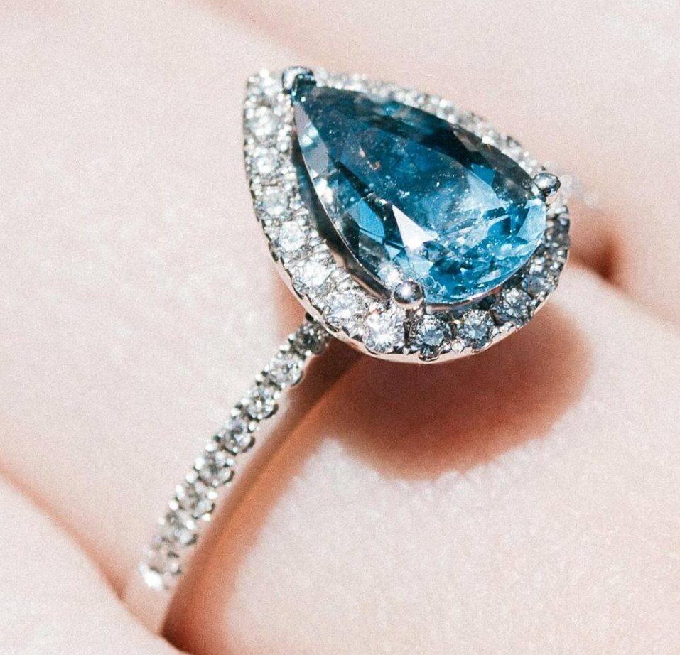 Close-up of a hand displaying an elegant blue gemstone ring in natural light.